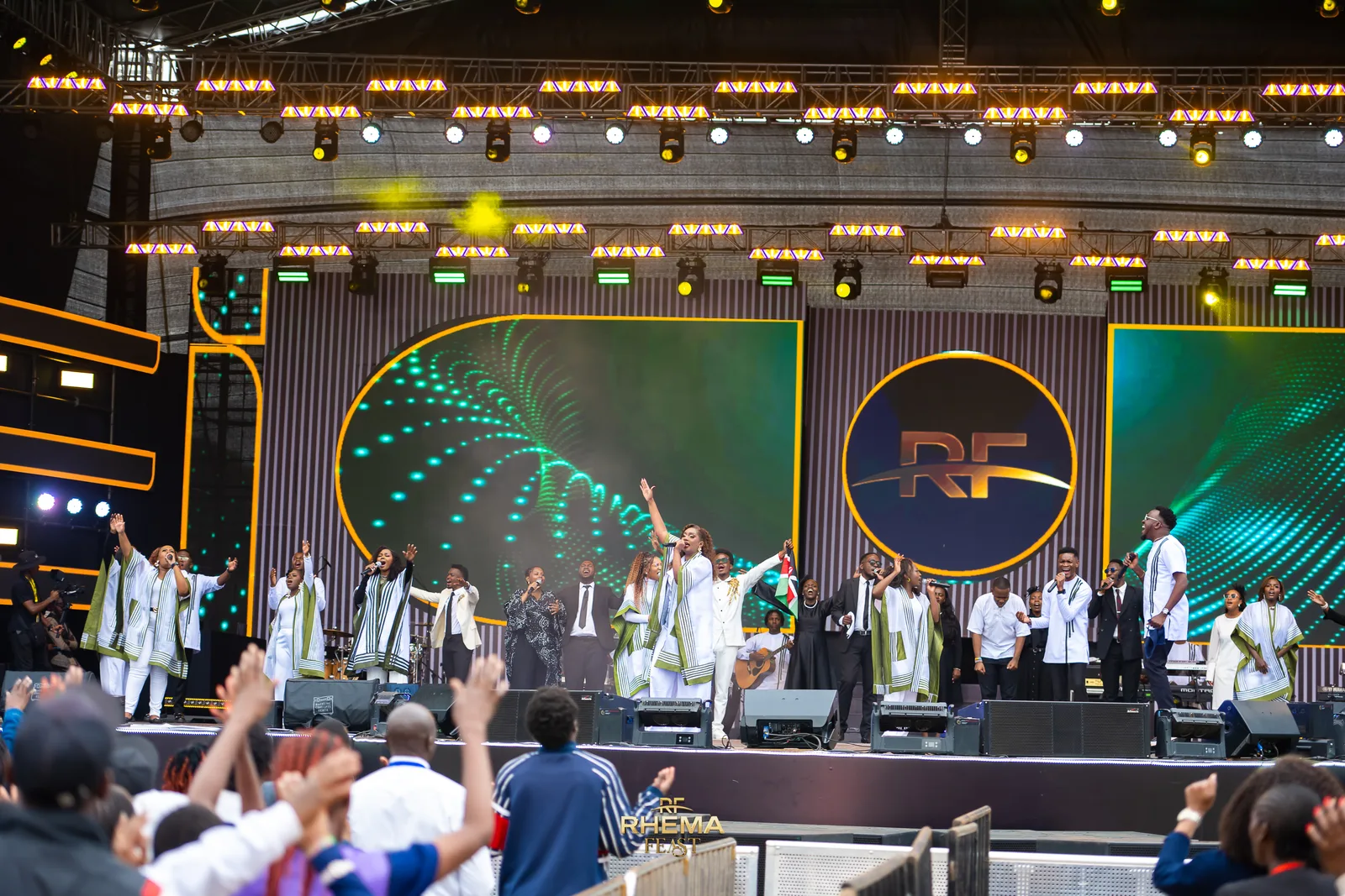 The worship team on the Rhema Feast stage, the RF mark lit behind them