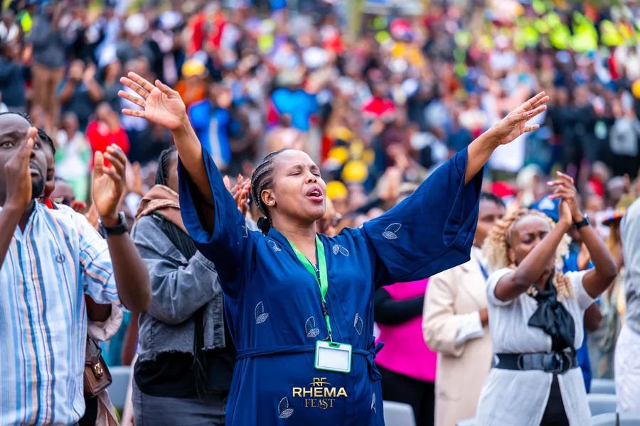A woman in the crowd with both arms stretched wide in worship