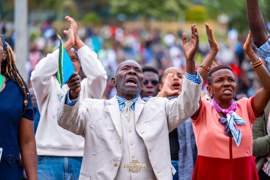 A man in the crowd with both hands raised and eyes shut