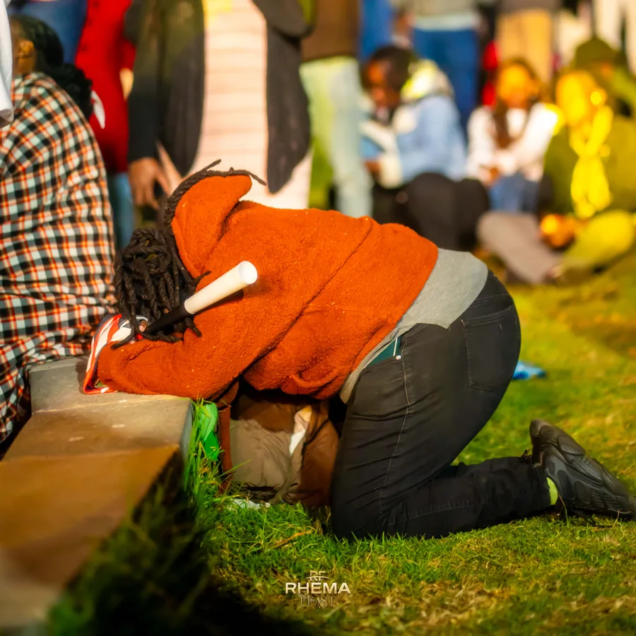 A worshipper kneeling face-down on the grass at Uhuru Park