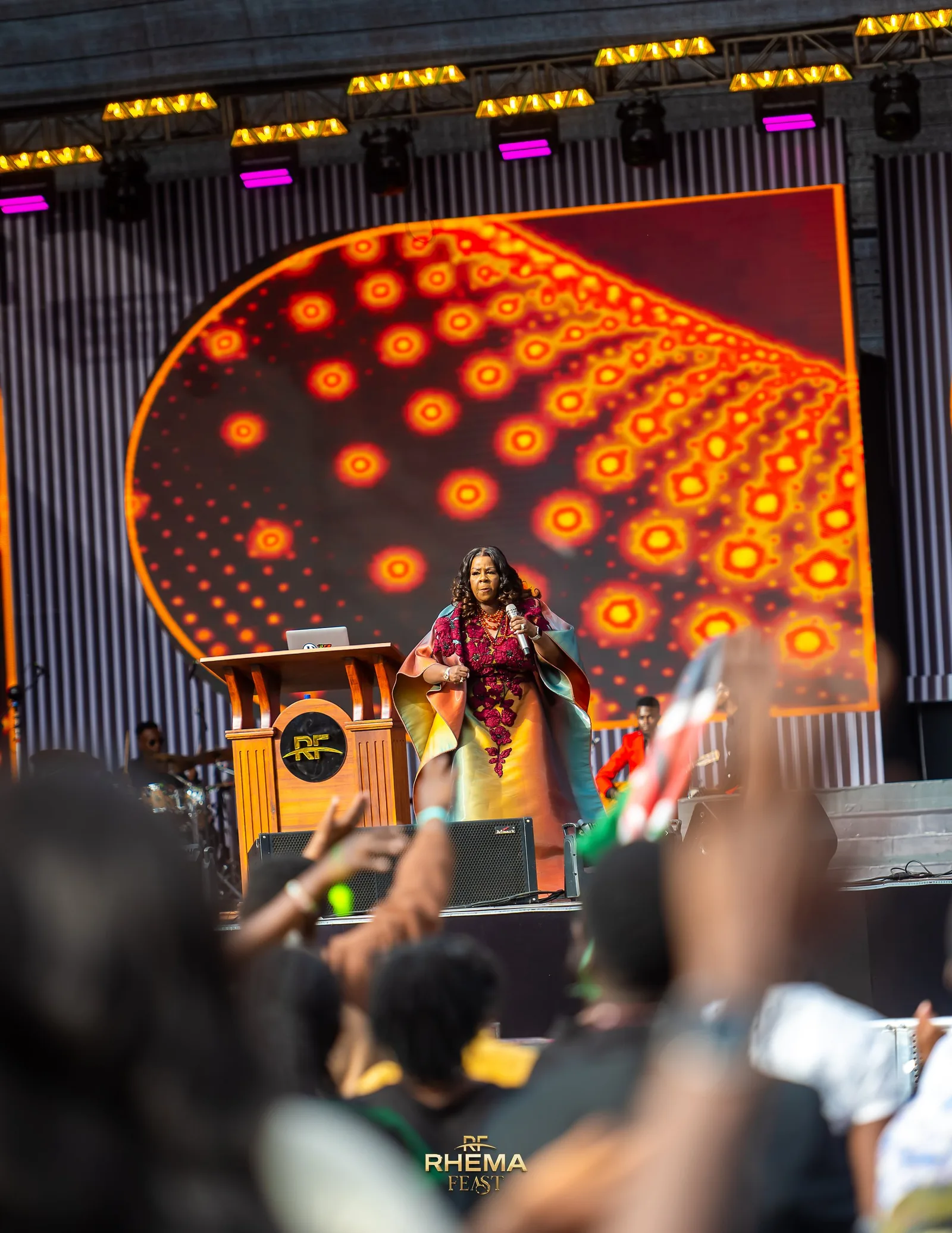 Lady Bishop Kathy Kiuna preaching, the crowd filling the frame behind her