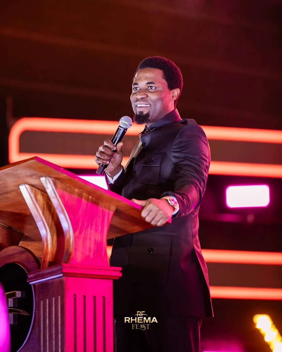 Apostle Michael Orokpo preaching at the podium, mic in hand