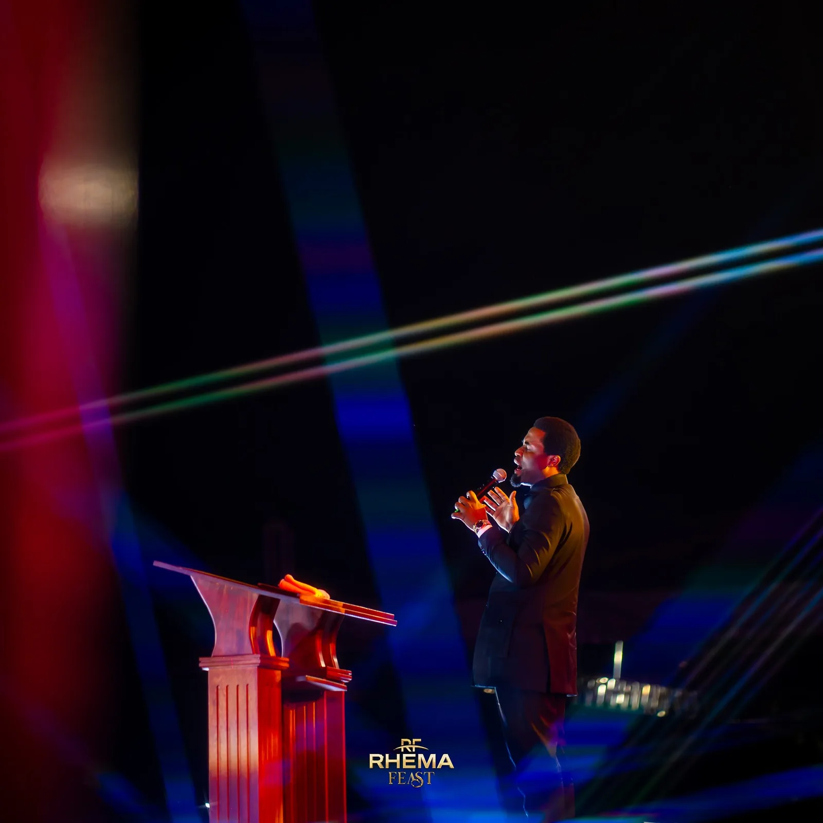 Apostle Michael Orokpo at the podium, the stage lit in red