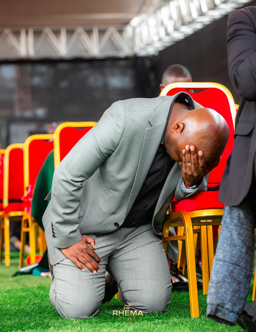 A man in a grey suit, bowed low on the platform