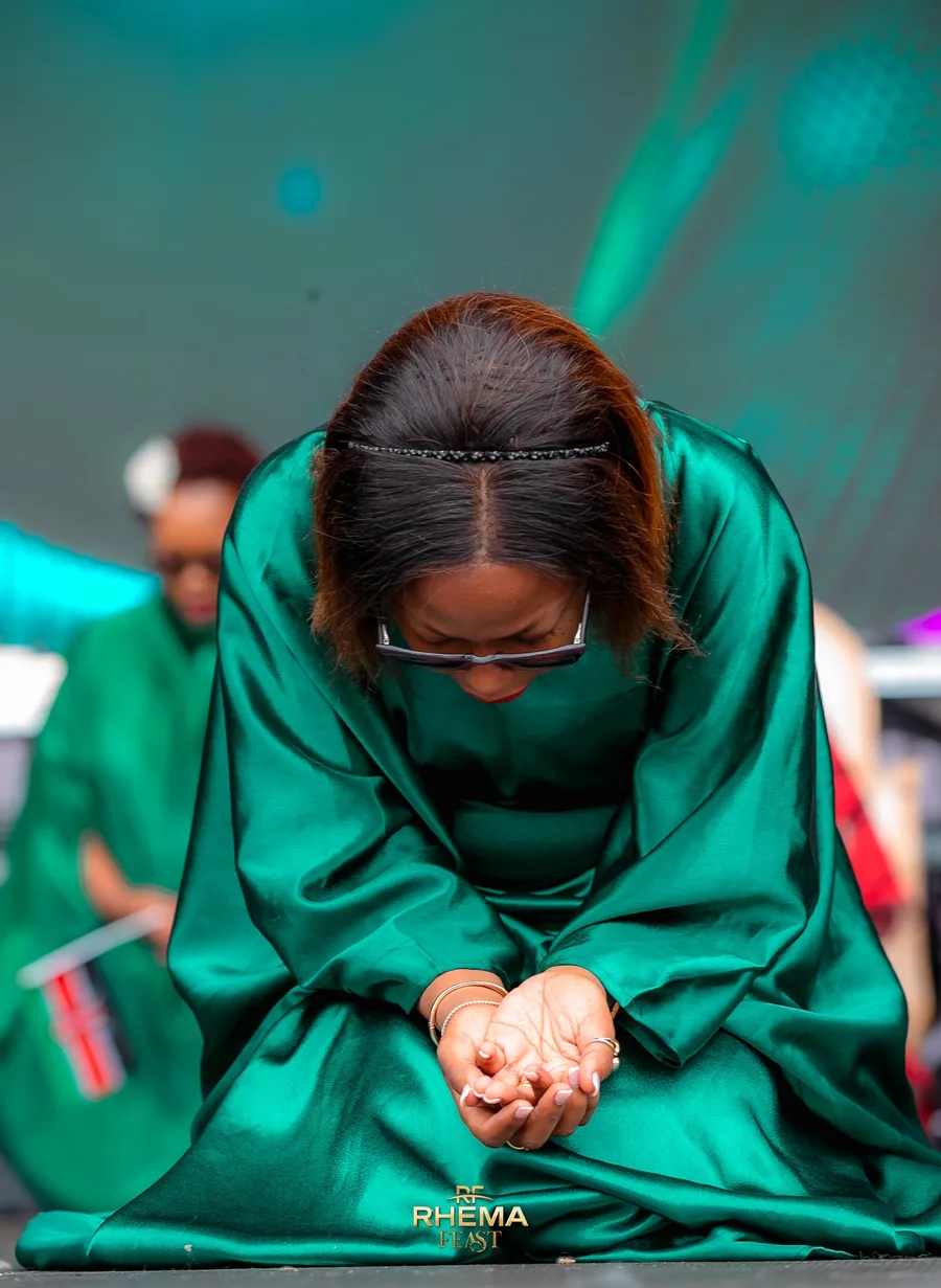 A woman in a teal scarf, head bowed in repentance