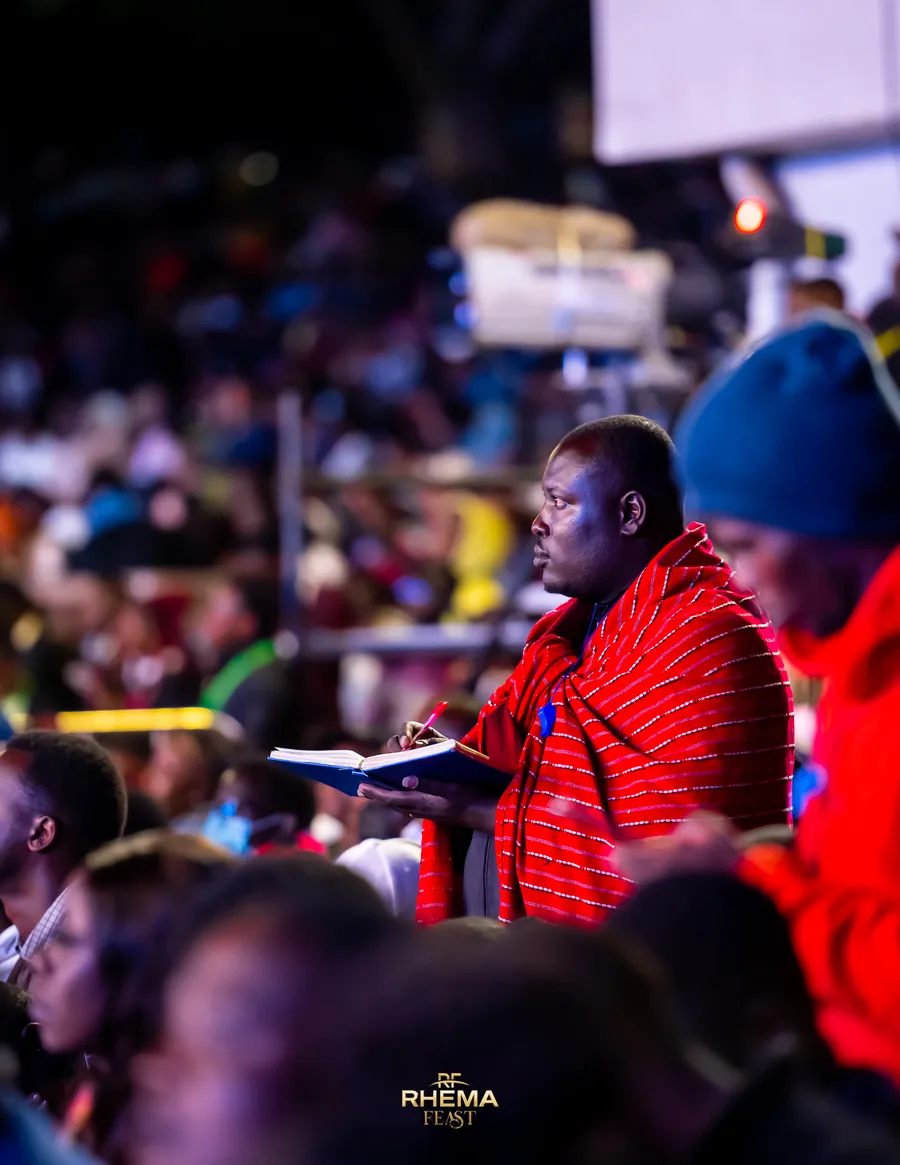 A delegate in Maasai dress taking notes in the crowd