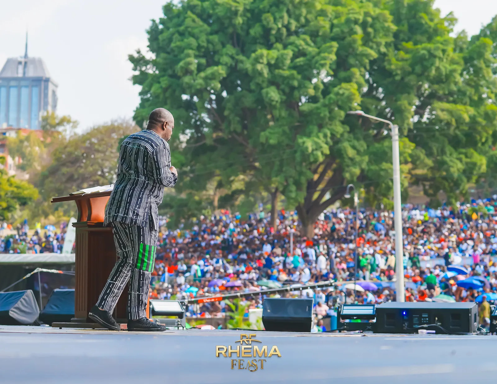 Apostle Poju Oyemade at the pulpit with the filled park beyond