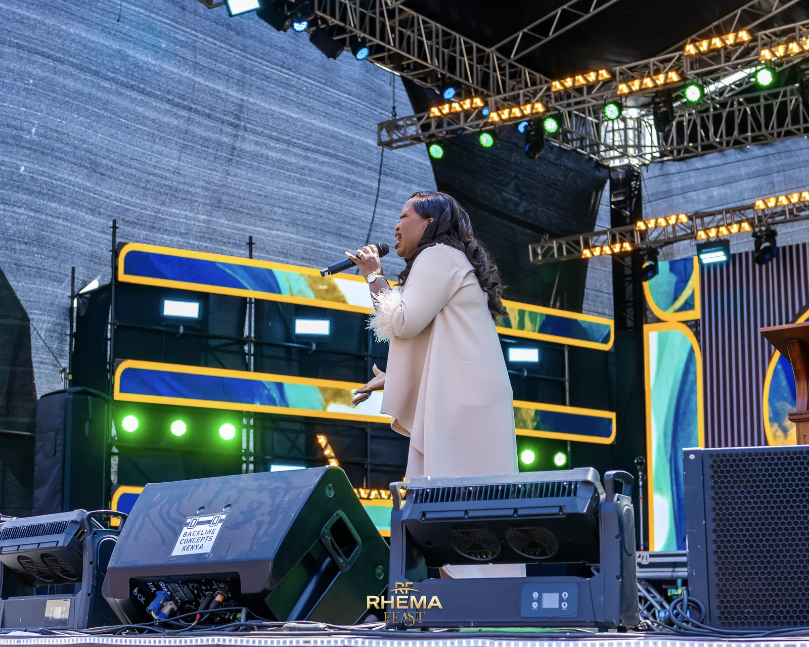 Rev. Lee Wambugu on the Rhema Feast stage in daylight on Day 5