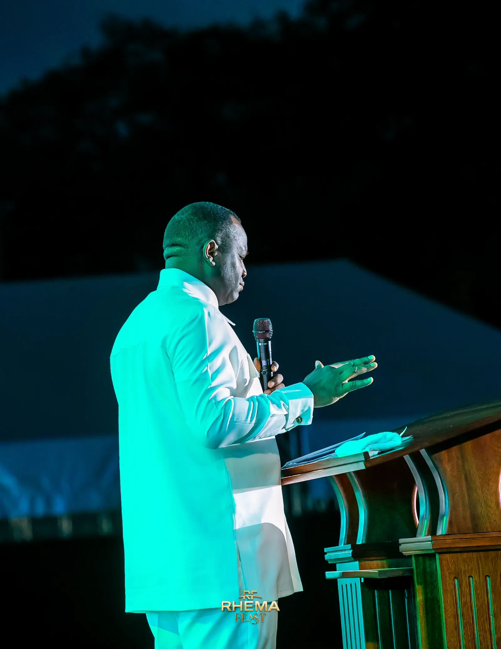 Dr. David Ogbueli with an open hand extended over the pulpit