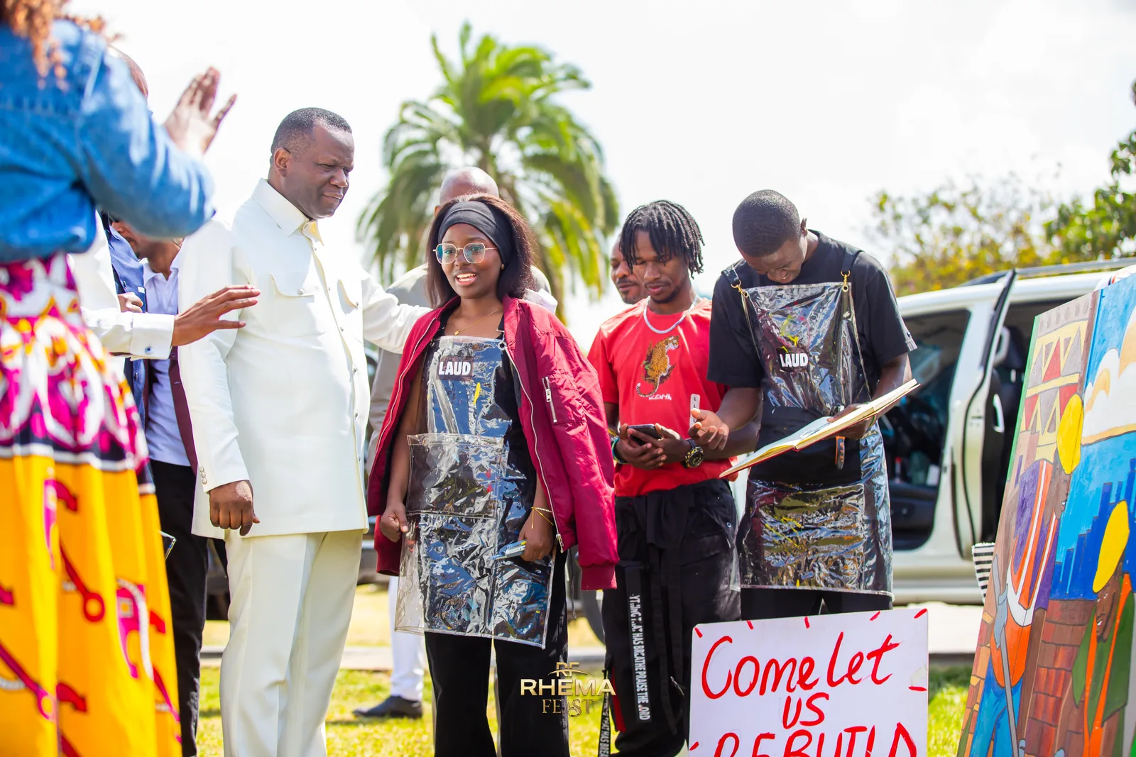 Young artists outside the tent holding their painted canvases and a hand-lettered Come Let Us Rebuild sign